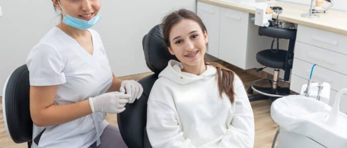 Orthodontist checking brackets on female teeth.