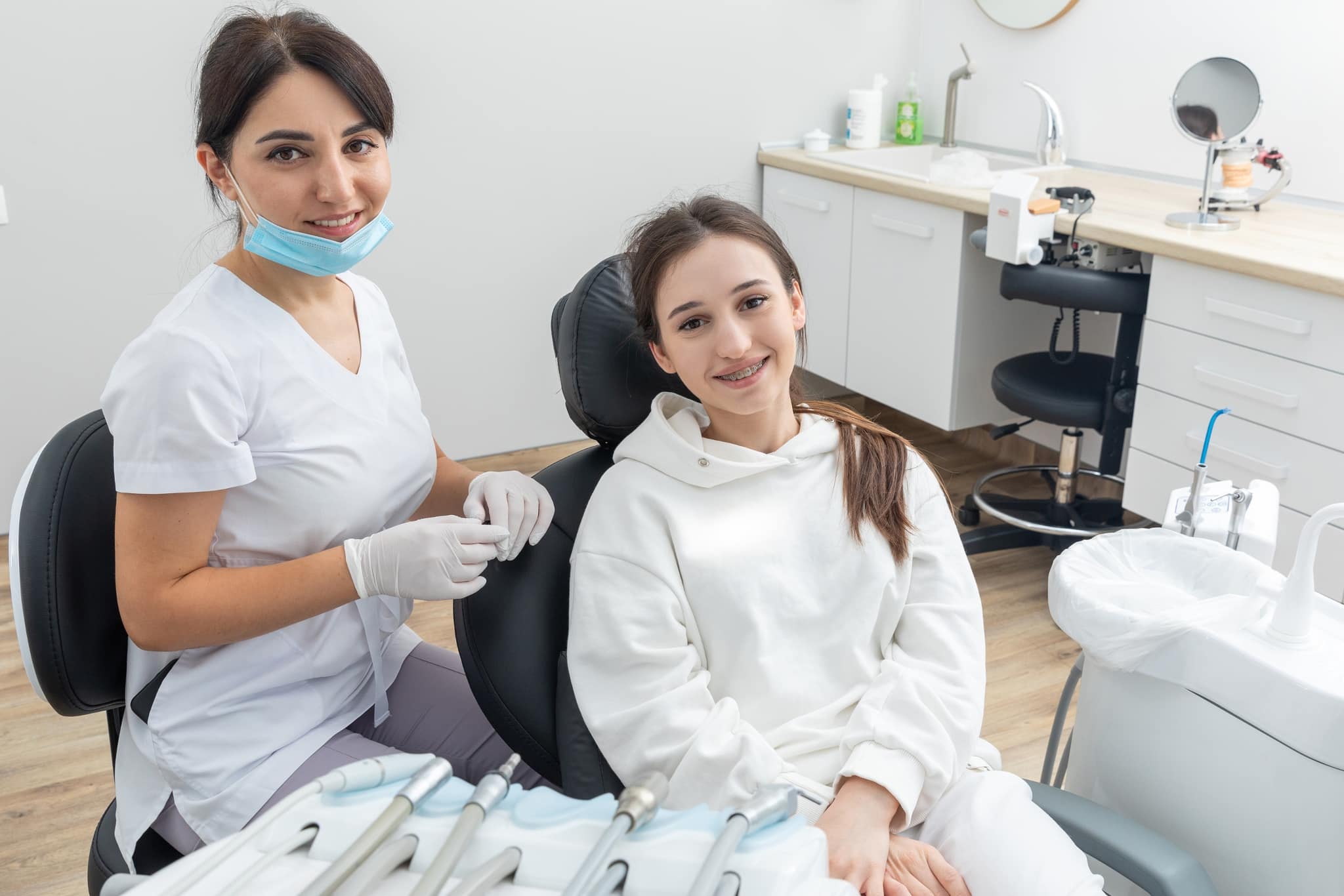 Orthodontist checking brackets on female teeth.