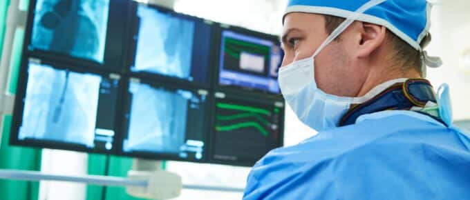 Male surgeon doctor at operation looking at xrays on a large screen.