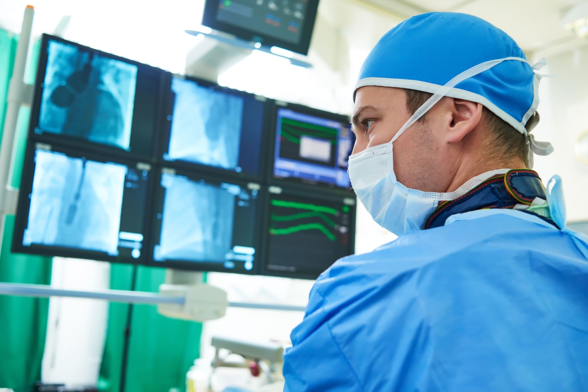 Male surgeon doctor at operation looking at xrays on a large screen.