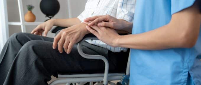 Caring nurse and a contented senior man in a wheel chair at home.