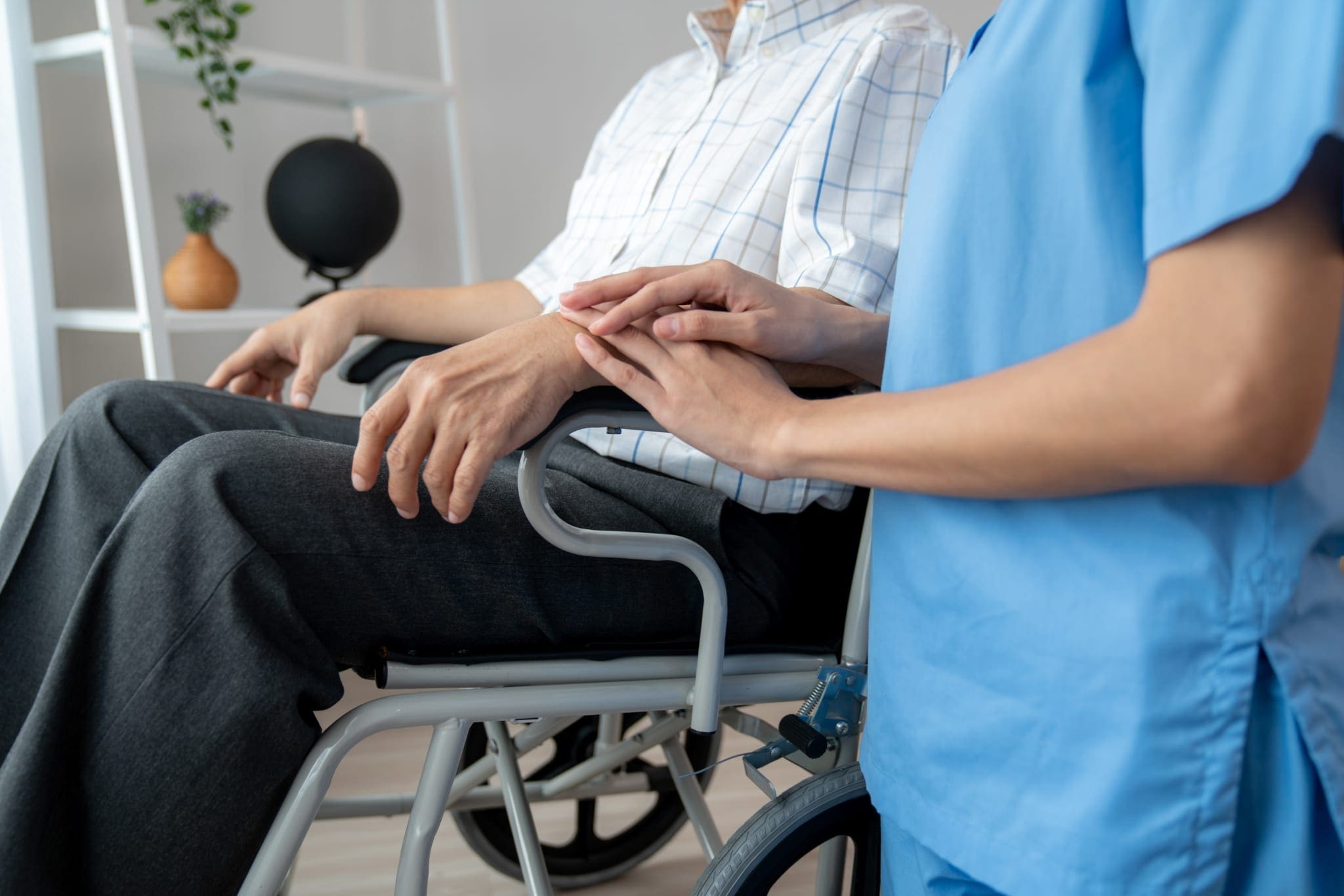 Caring nurse and a contented senior man in a wheel chair at home.