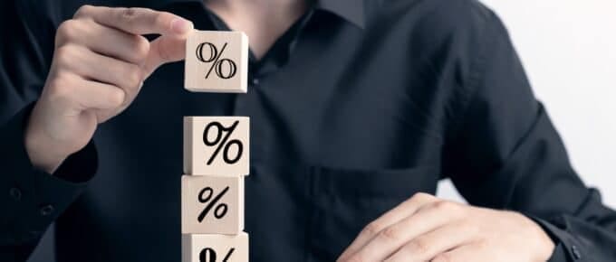 Hand building a tower from wooden cubes with percent symbol