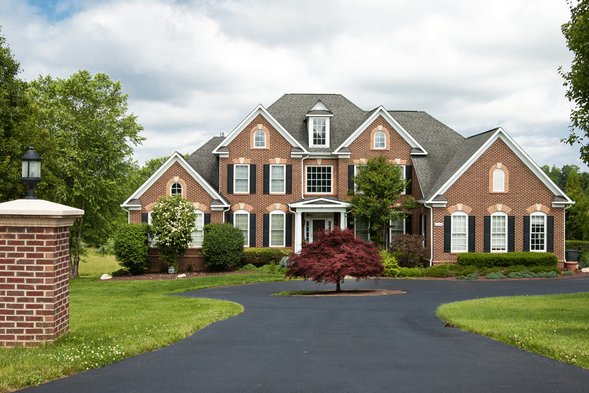 large brick home with manicured lawn.