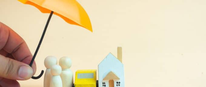 Man hand use toy orange umbrella for coverage of family, car and home.