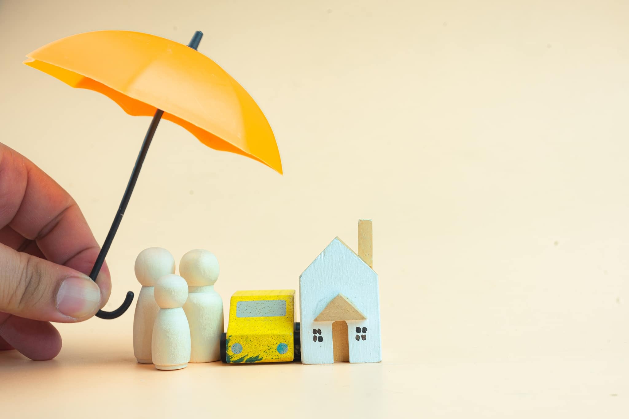 Man hand use toy orange umbrella for coverage of family, car and home.