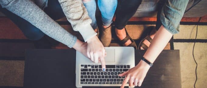 Parents and student pointing to laptop to look at how to pay for college
