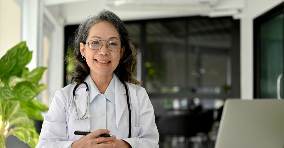 Professional Asian aged female doctor specialist working at her desk, using laptop computer