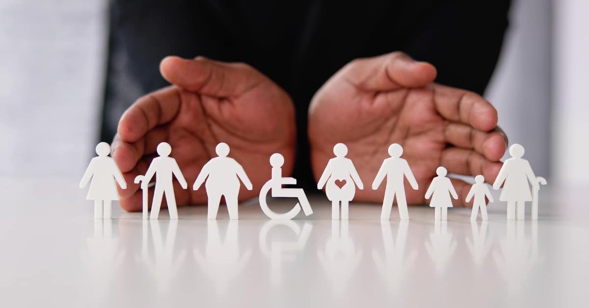 two hands resting on a white table with figurines of human beings sitting on the table in front of the hands