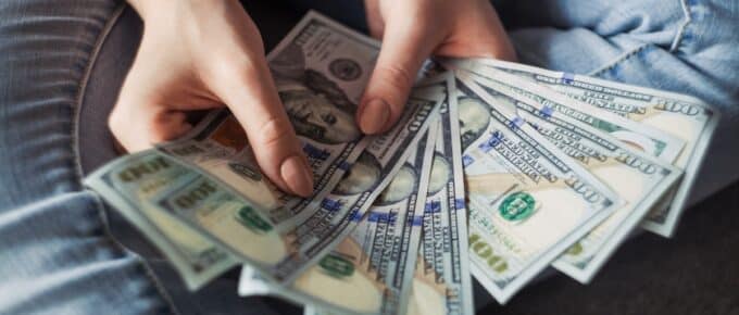 two hands holding several piles of money
