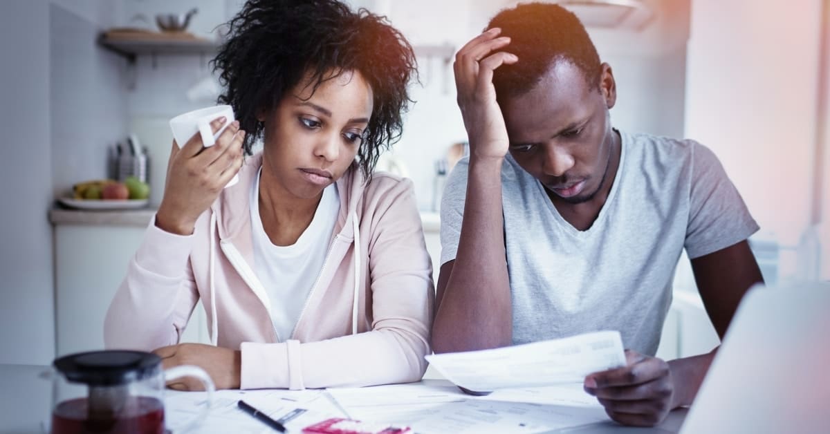 Stressed african american couple reviewing their finances sitting at kitchen table