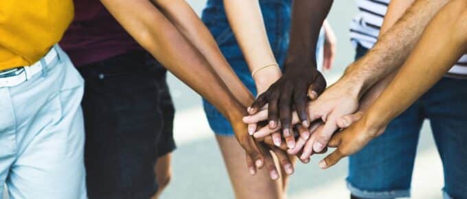 Close up multi ethnic group of young students stacking hands together