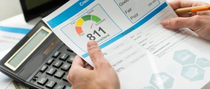holding a credit report form with credit score chart on it over a desk with a keyboard