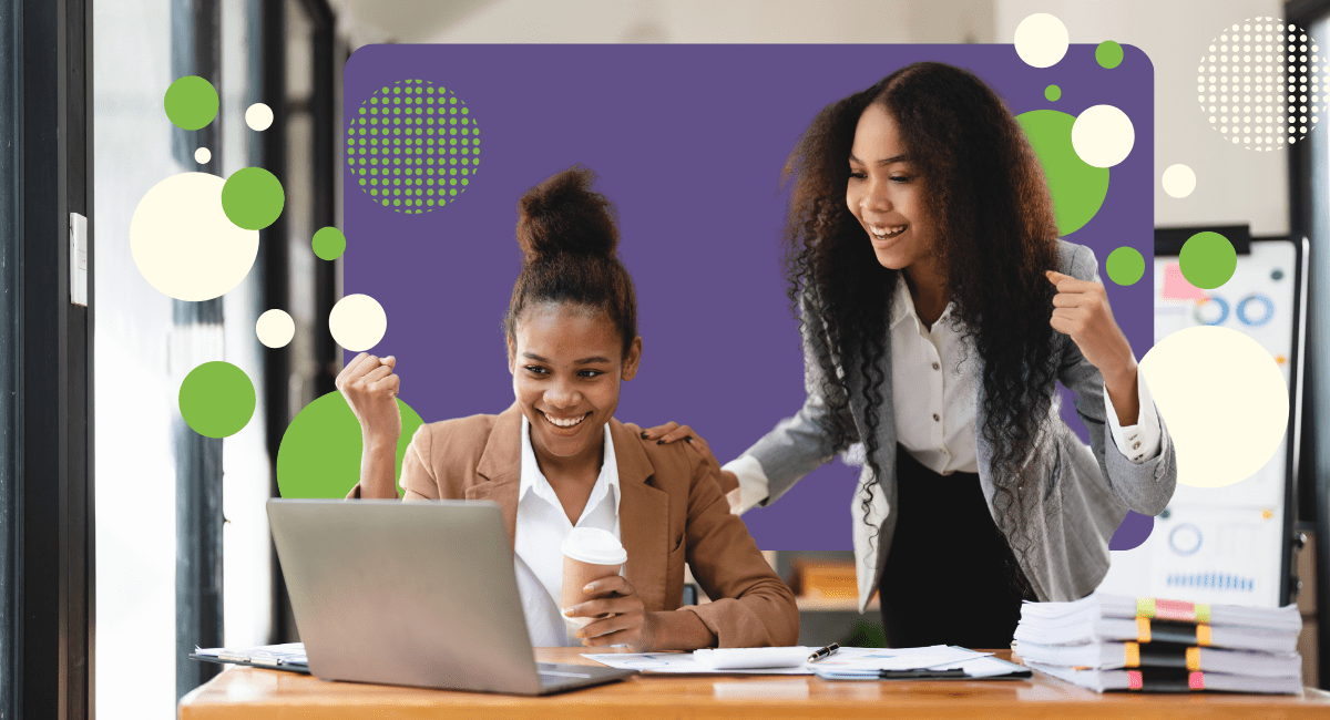 two female office workers looking at laptop, looking very happy