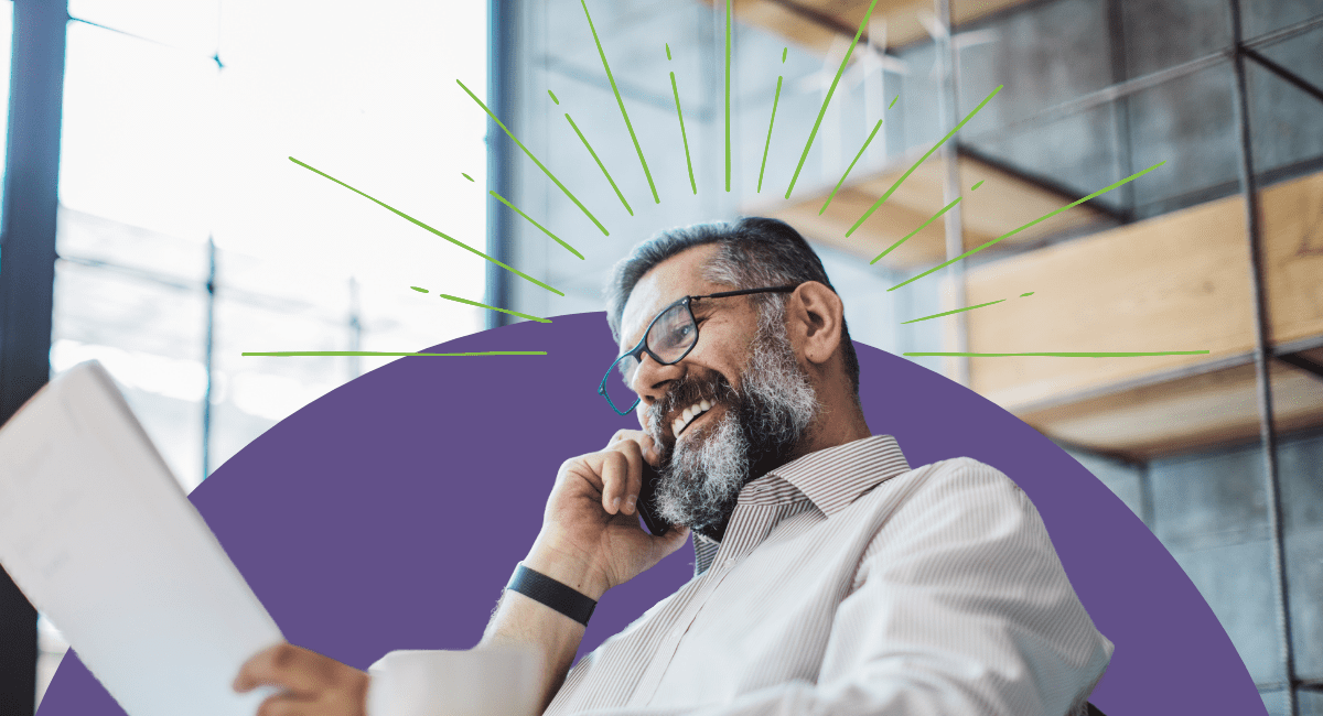 older male office worker talking on phone, smiling and looking at paper