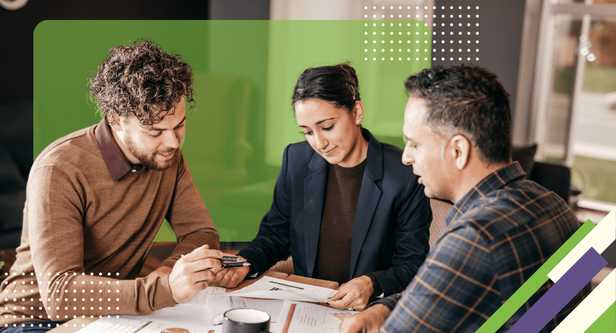 three people sitting around table, looking at papers and comparing