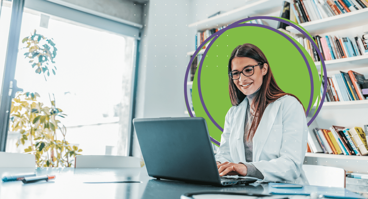 female office worker with long brown hair and glasses smiling looking at laptop