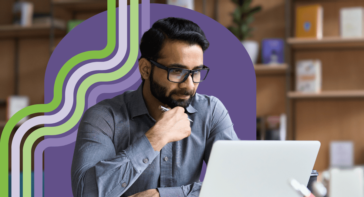 man with dark hair and glasses looking at laptop, thinking deeply