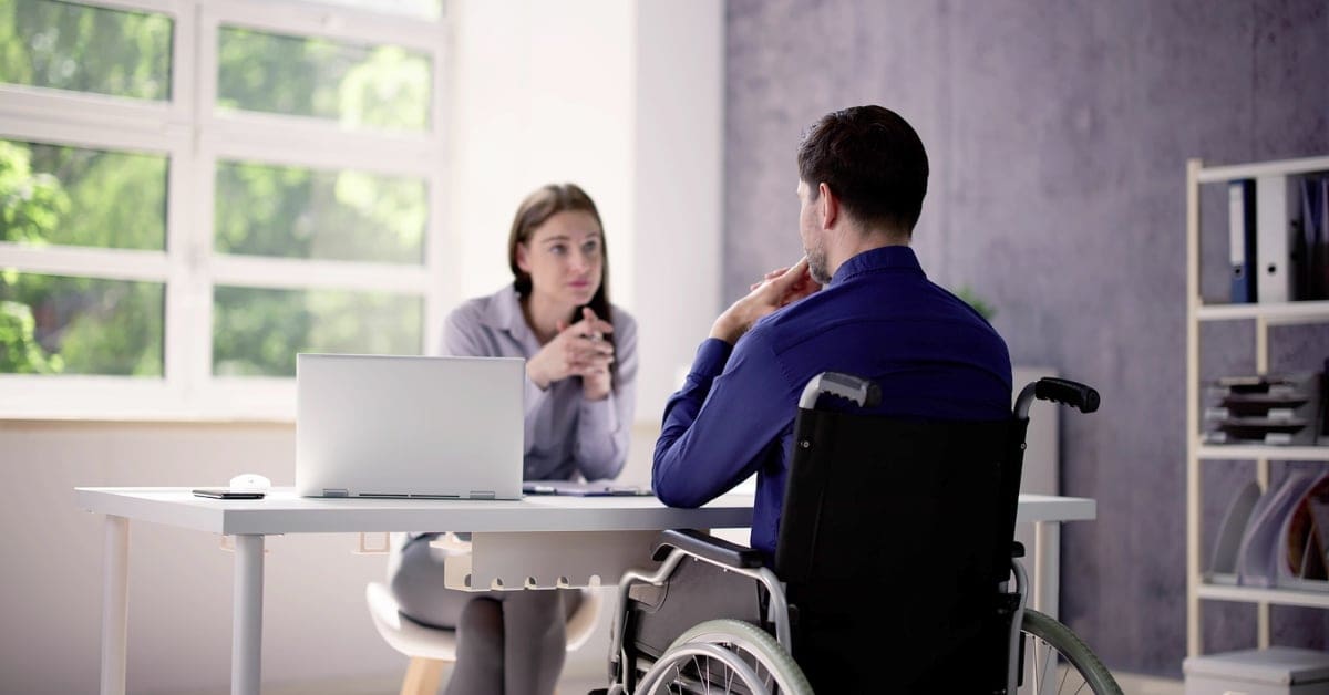 man and woman sitting across from each other at a desk in an office