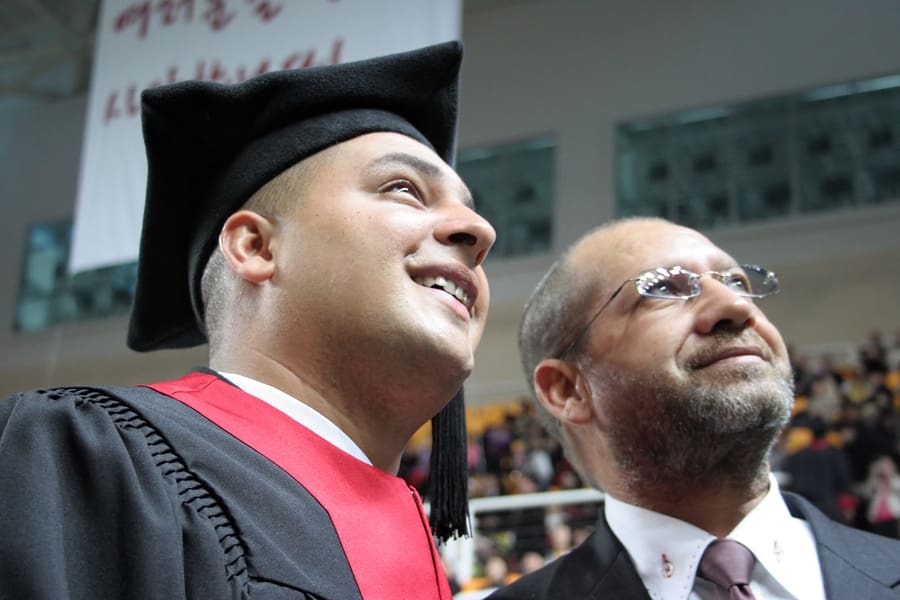 male in gap and gown with father looking up