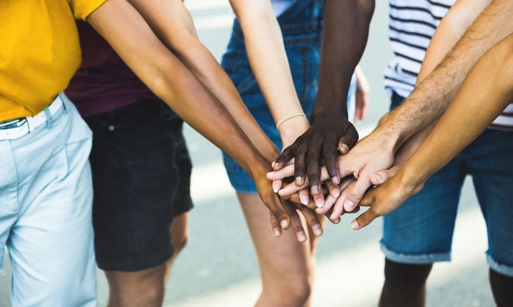 Close up multi ethnic group of young students stacking hands together