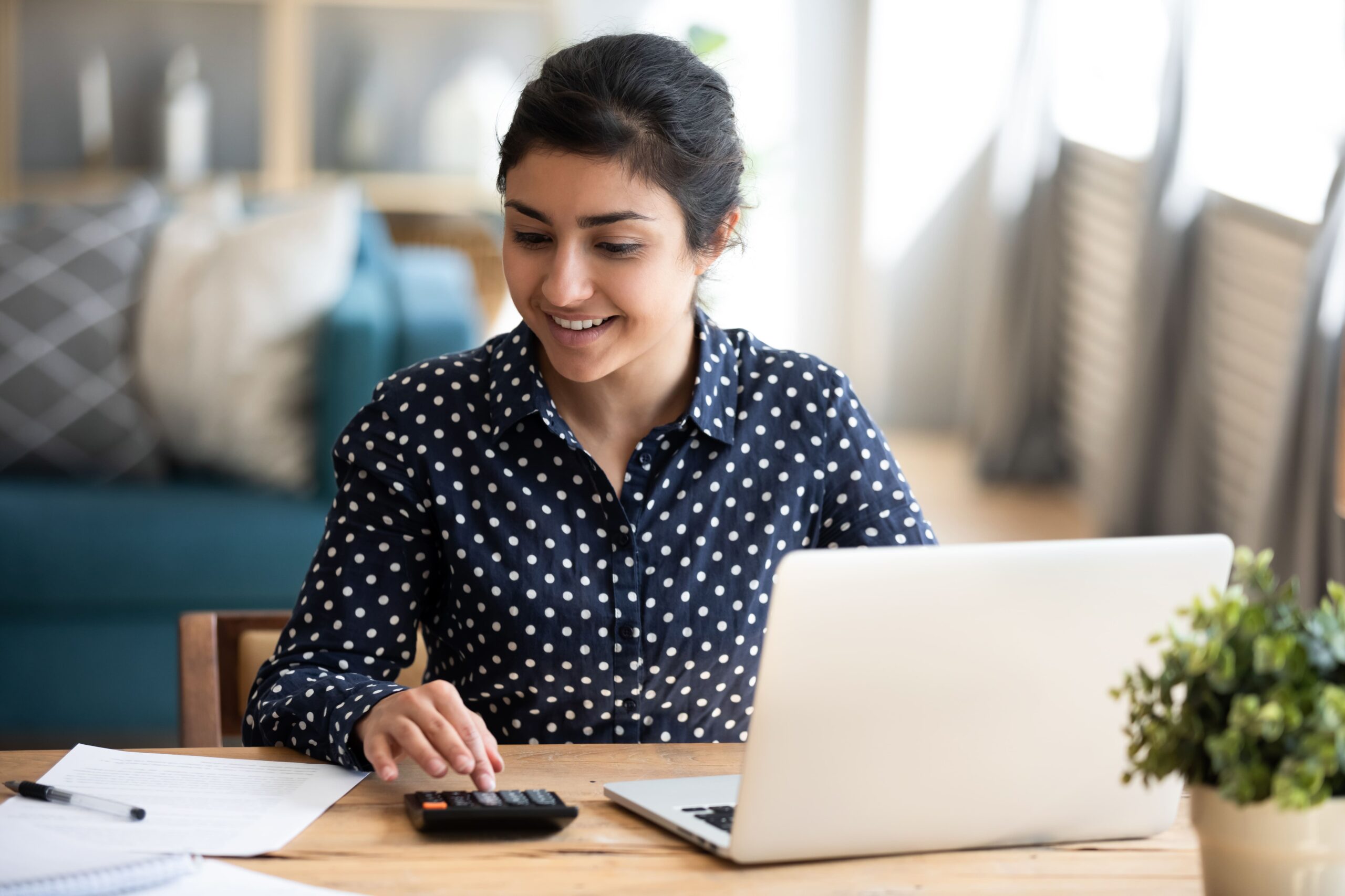 Indian woman with a computer and calculator planning her student loan refinancing.