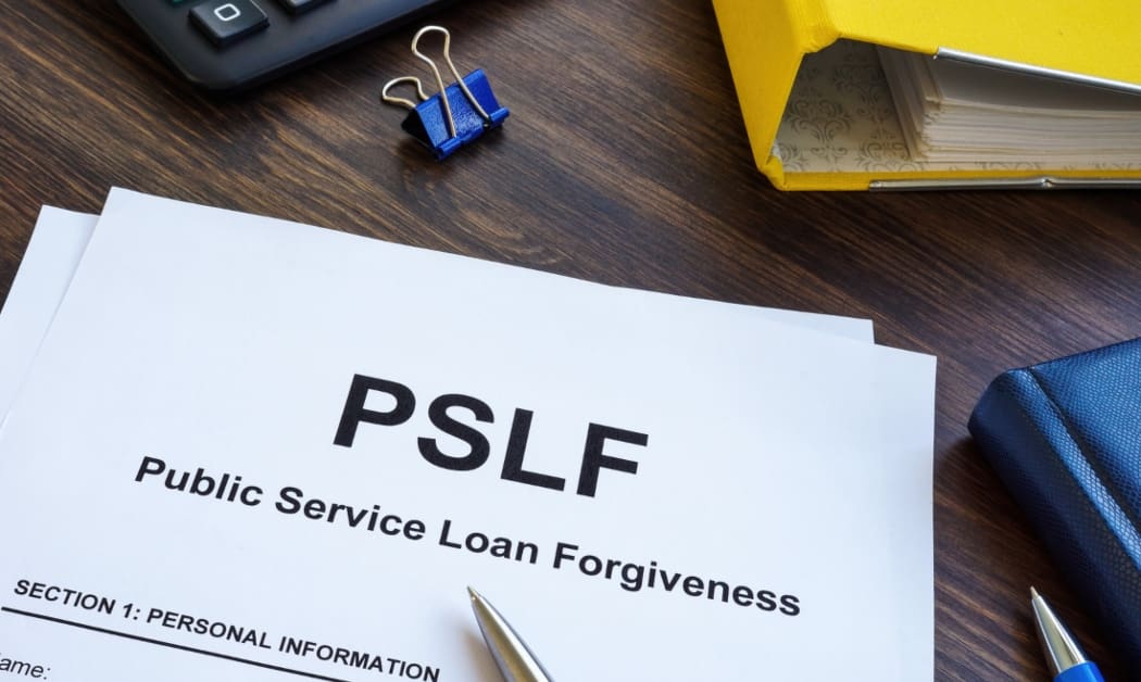 Papers foe Public Service Loan Forgiveness PSLF on the wooden desk surface