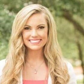 blonde female outside in lab coat smiling