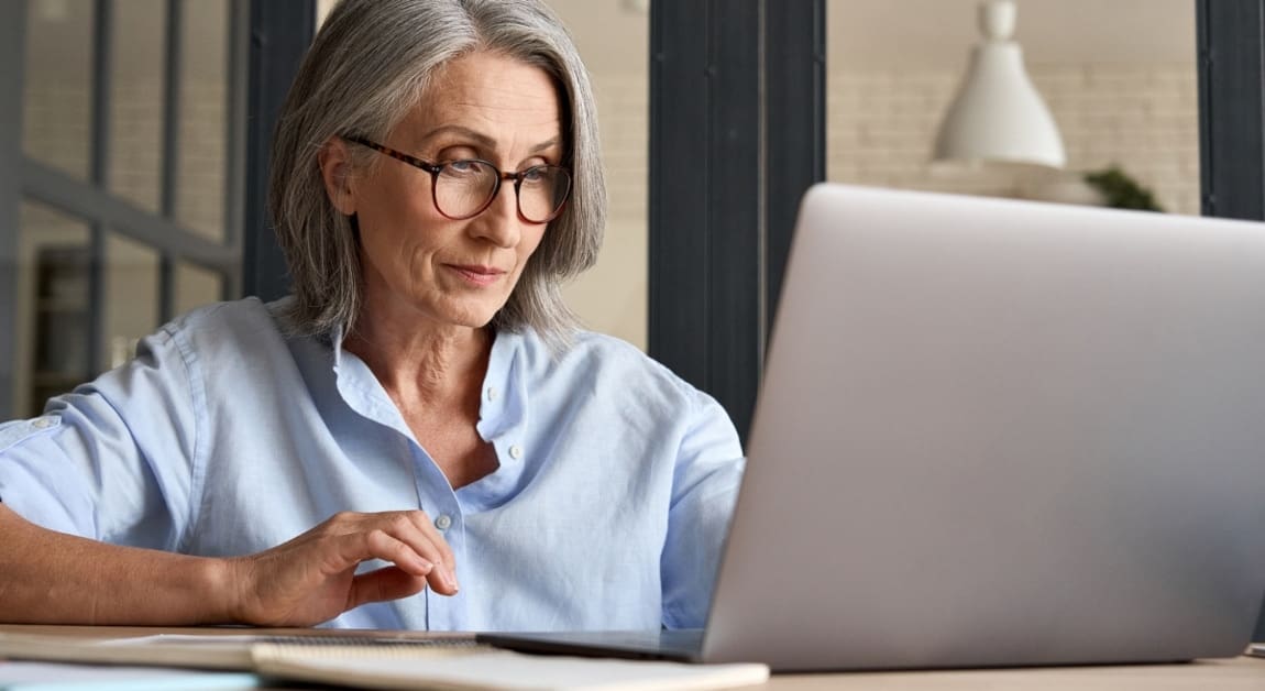 Mature adult 60s aged woman working at laptop