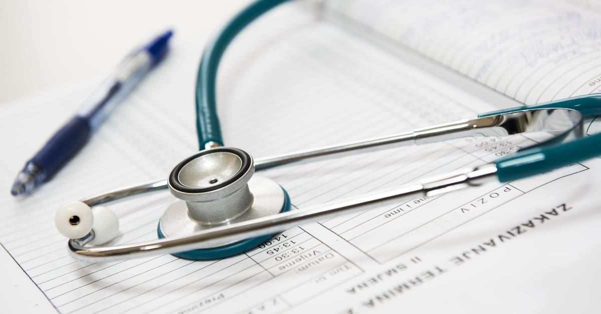 Stethoscope on a desk next to a pen