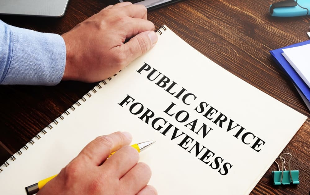 Public service loan forgiveness program PSLF written in bold letters on a white sheet of paper sitting on the desk