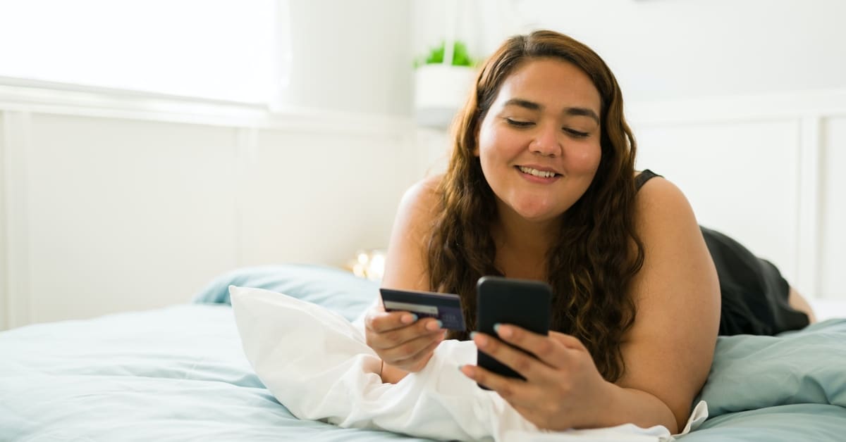 woman holding phone and credit card thinking about paying medical bills