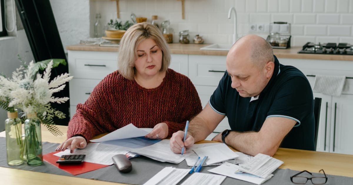 Man and woman sitting at a kitchen table reviewing tax paperwork