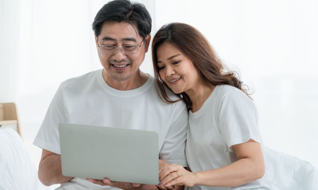 married couple looking at parent plus loan options on a laptop