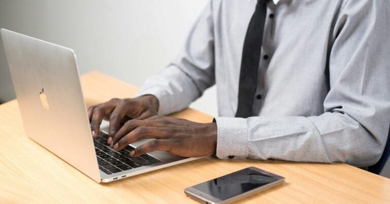 man typing on laptop sitting at desk.