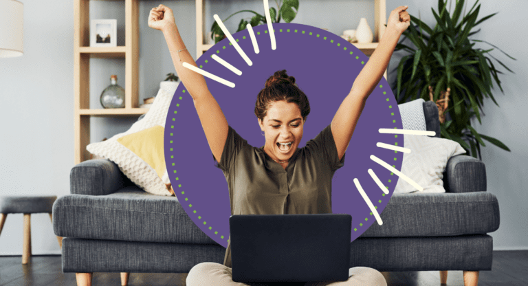 woman celebrating good news sitting on the floor with laptop