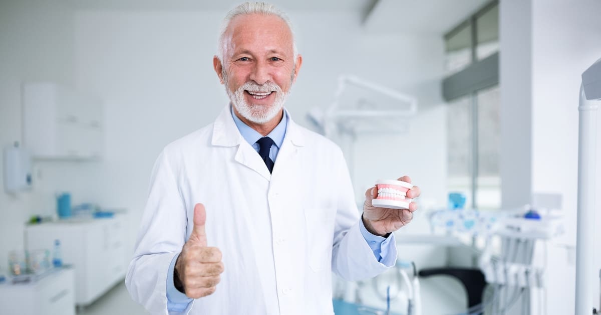 Dentist in dentist's clinic holding a dental model