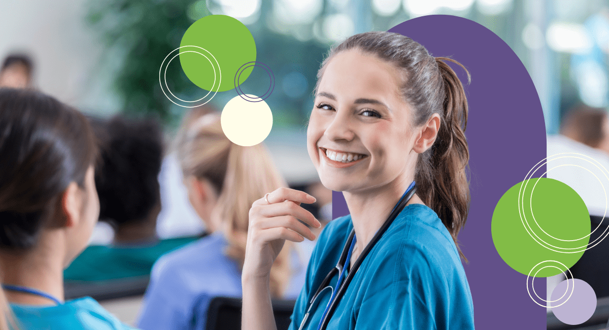 Female nurse wearing blue scrubs smiling in a group of medical professionals