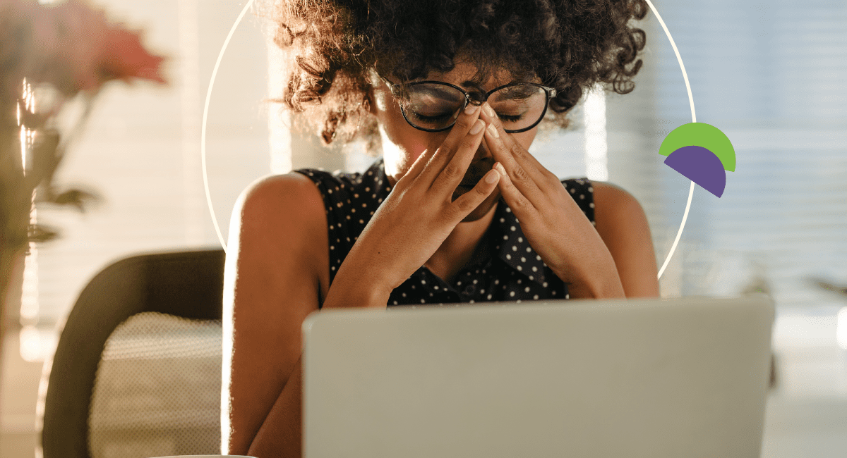 woman with glasses and curly hair looking at her laptop, very stressed