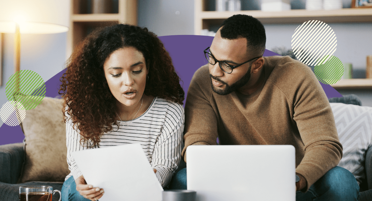 couple looking at paper together having a discussion, laptop in front of them