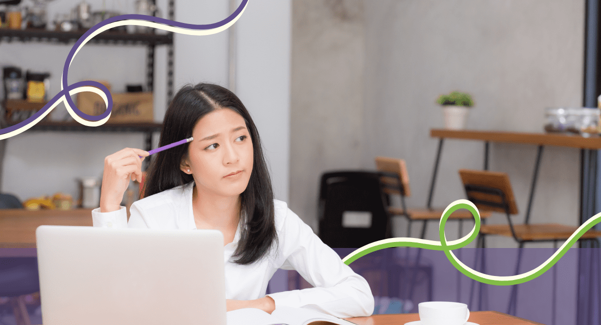 Asian female working in a cafe with laptop and book, thinking