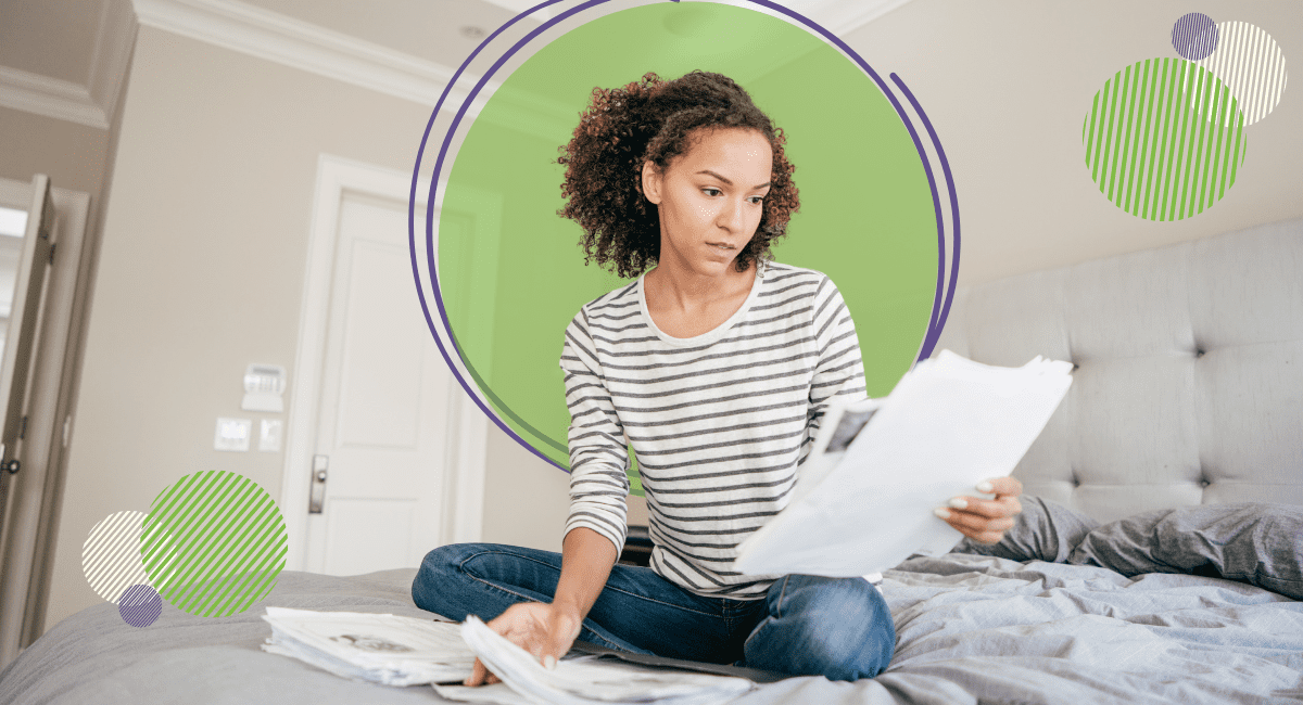 young female looking at papers on bed