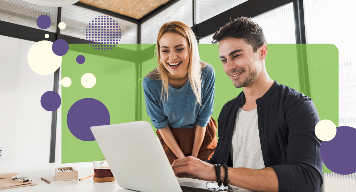 two people looking at a laptop screen, smiling, in an office with large windows