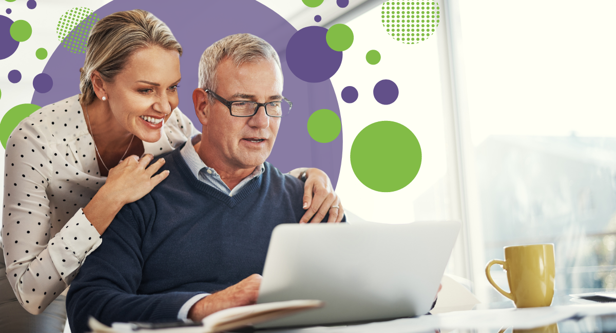 man and woman looking at laptop sitting at a desk in front of a large window that overlooks scenic view