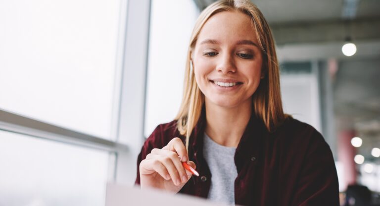 Blonde woman filling out paper IDR application.