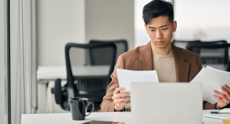 Professional business man sitting at desk in office reviewing documents